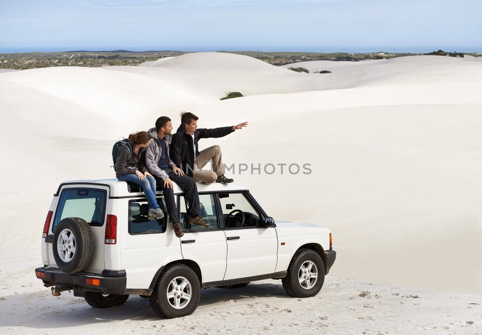 Friends, people on car in desert and travel for tourism in Dubai for safari, road trip and view. Adventure, journey and transportation with offroad vehicle or 4x4 on vacation for break outdoor by YuriArcurs