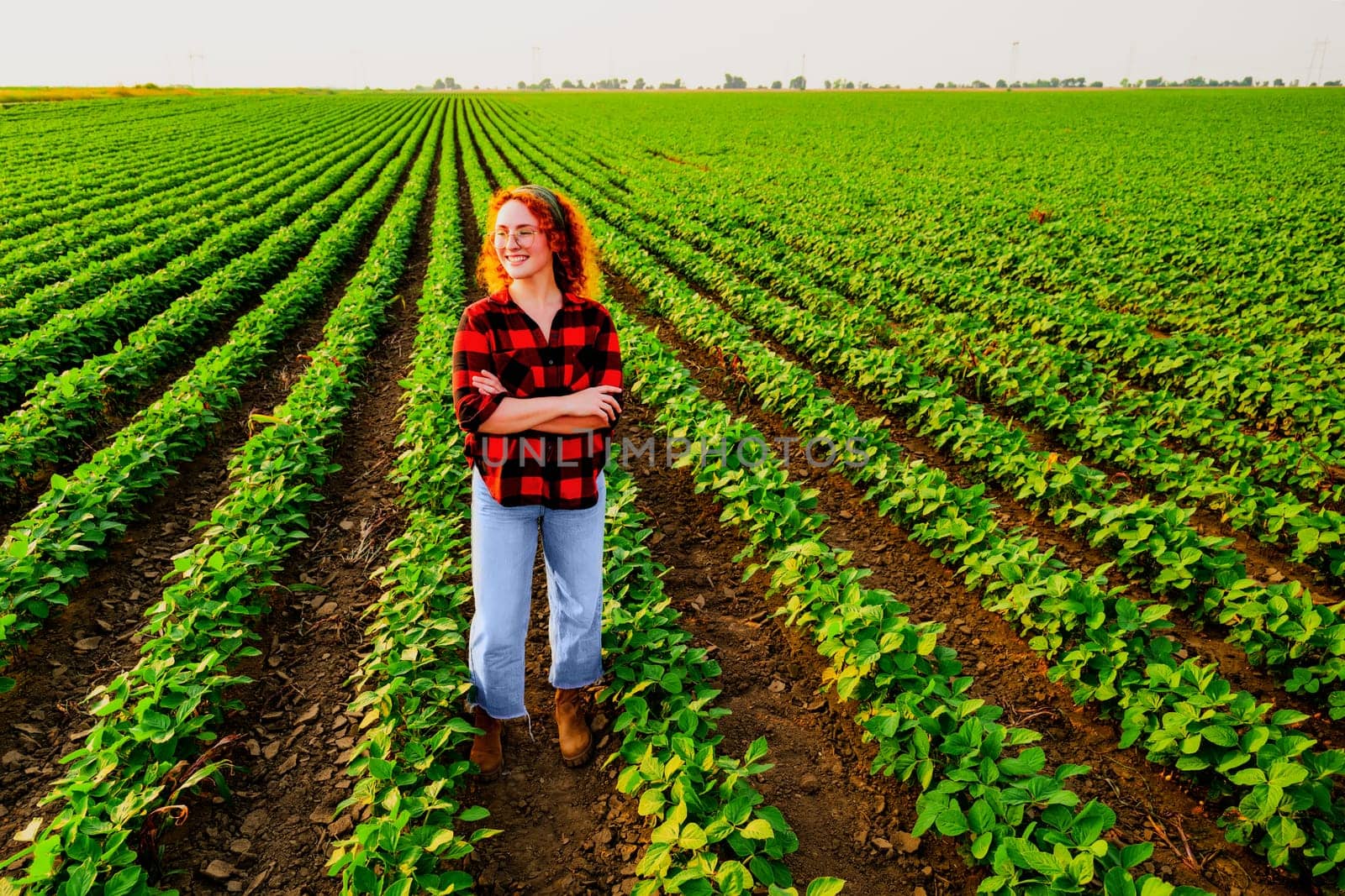 Portrait of female farmer who is cultivating soybean. She is satisfied with good progress of plants. Agricultural occupation.