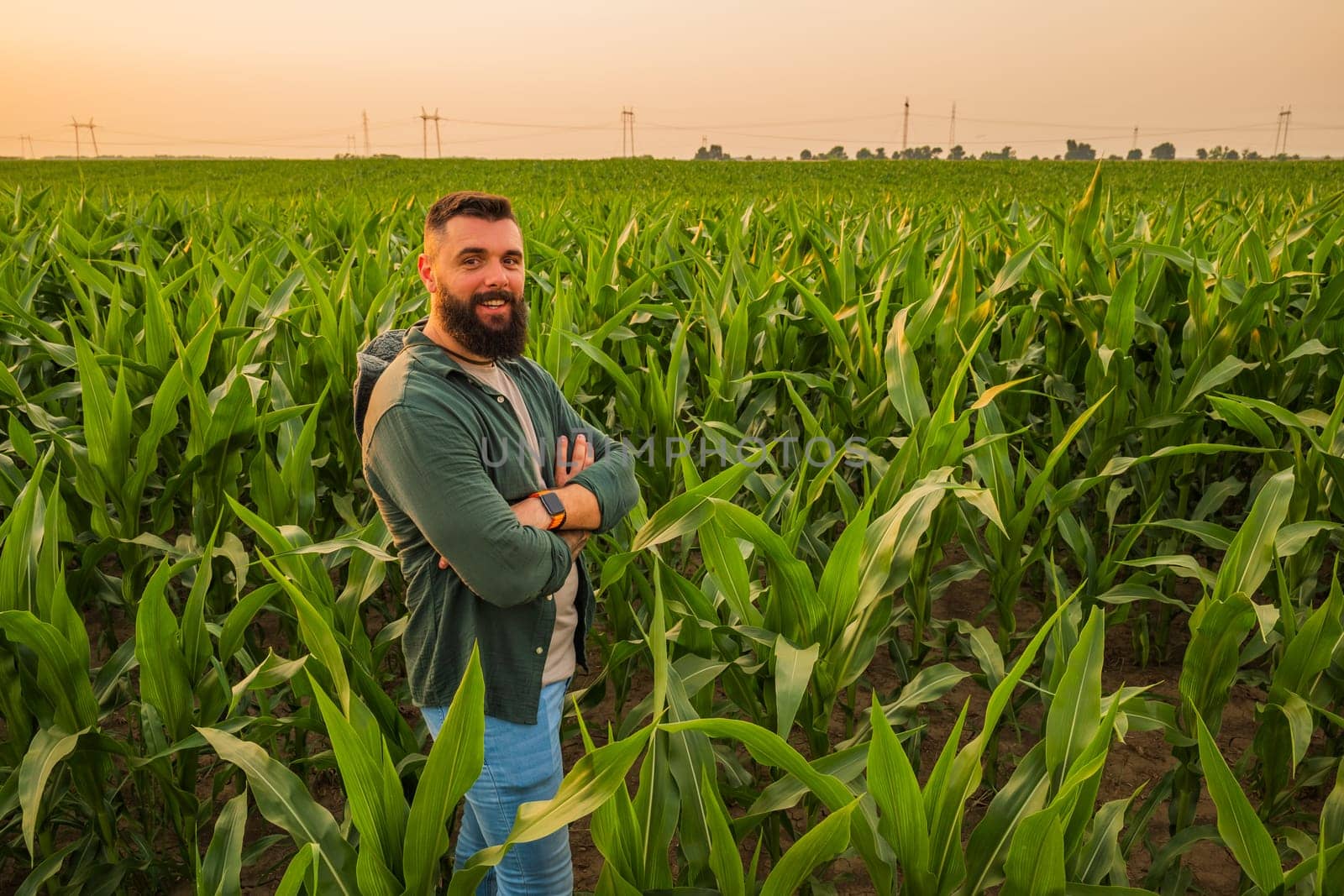 Portrait of farmer who is cultivating corn. He is satisfied with good progress of plants. Agricultural occupation.