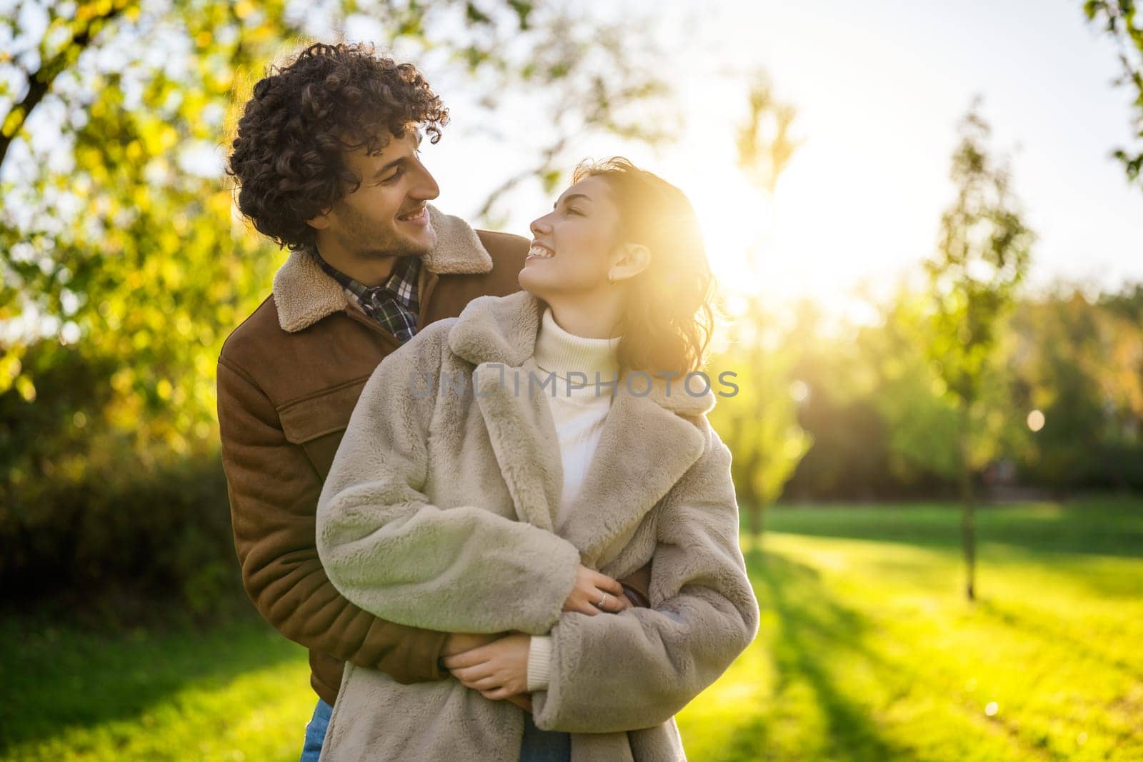 Happy loving couple embracing in park in sunset.