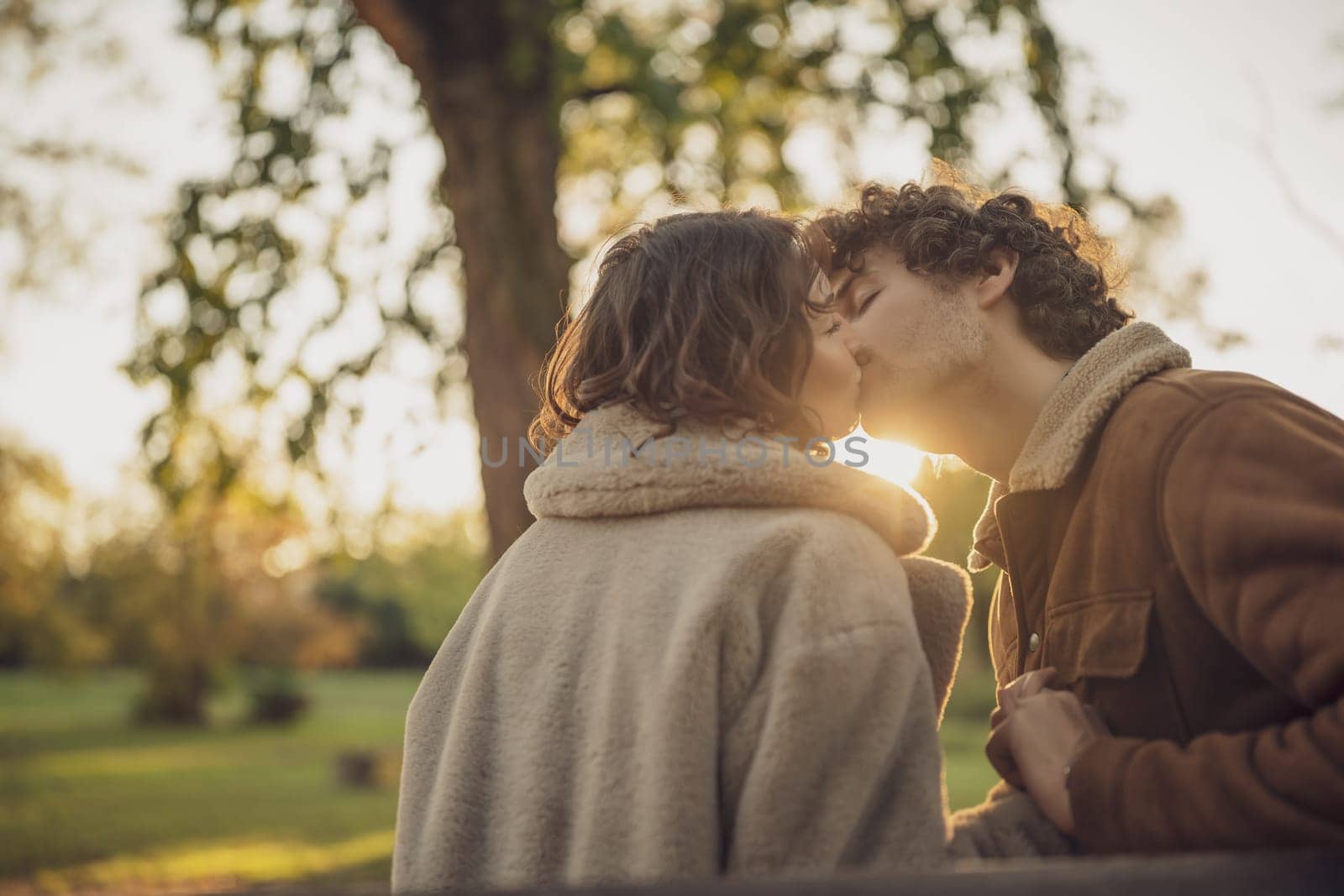 Portrait of happy loving couple in park. Man and woman kissing.