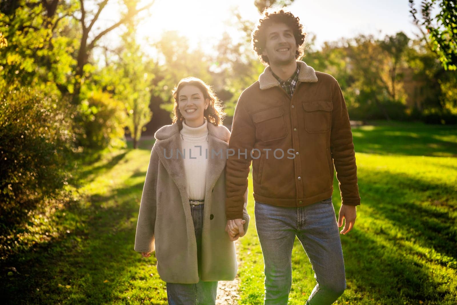 Portrait of happy loving couple walking in park in sunset.