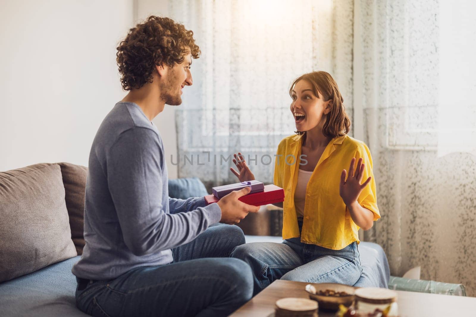 Portrait of young happy couple. Man is giving gift to his woman.