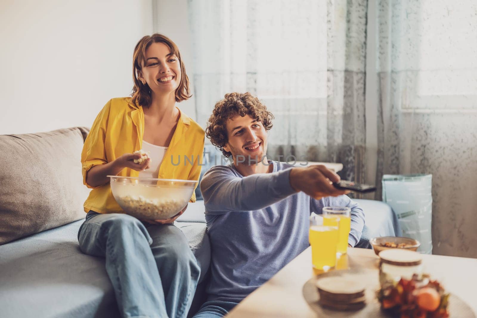 Portrait of young happy couple who is relaxing and watching TV at home.