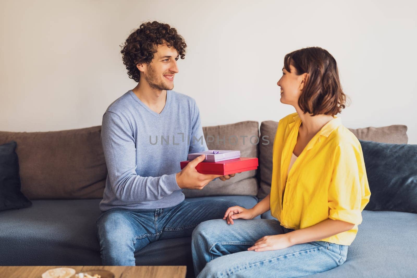 Portrait of young happy couple. Man is giving gift to his woman.