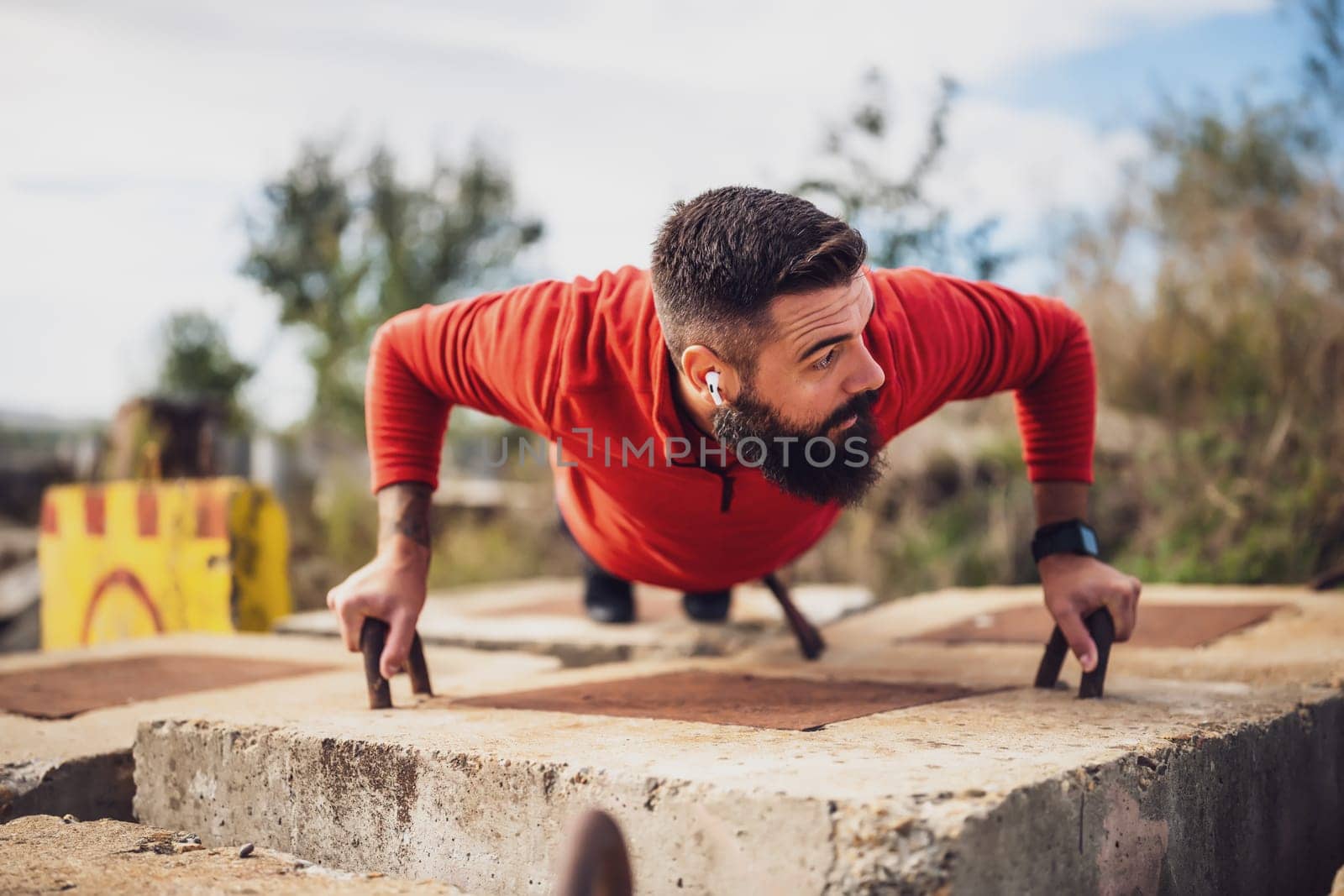 Young man is exercising outdoor. He is doing push-ups.