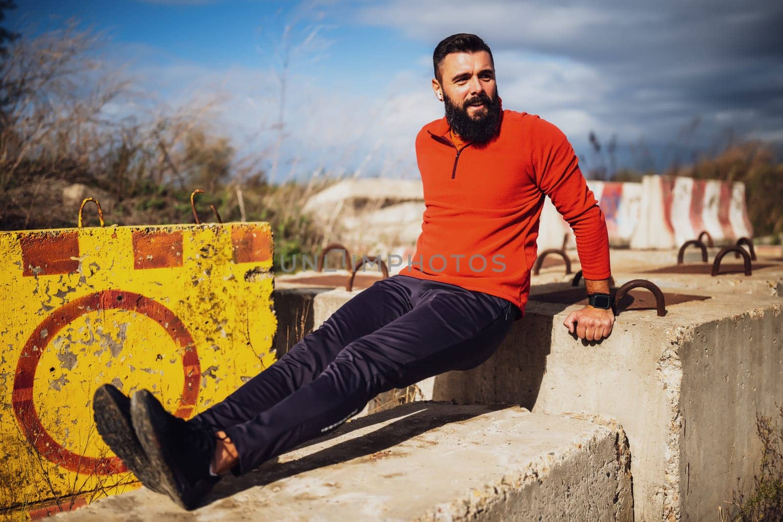 Young man is exercising outdoor. He is doing reverse push-ups.