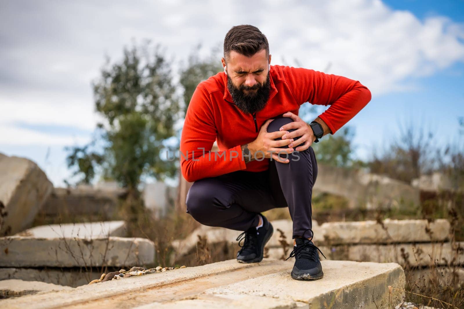 Young man is having pain in knee while exercising and jogging outdoor.