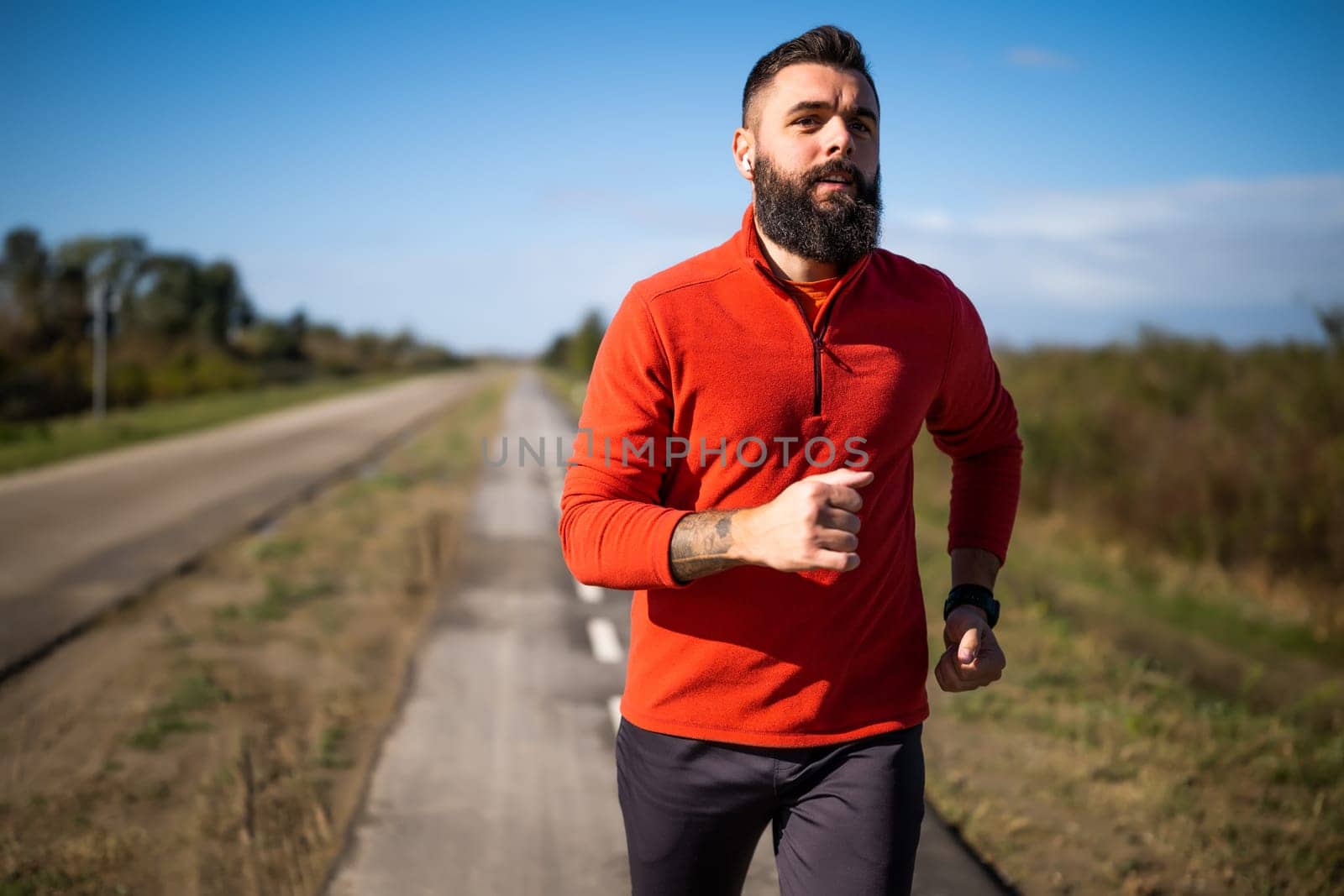 Adult man is jogging outdoor on sunny day.