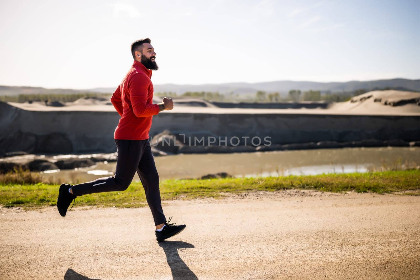 Adult man is jogging outdoor on sunny day.