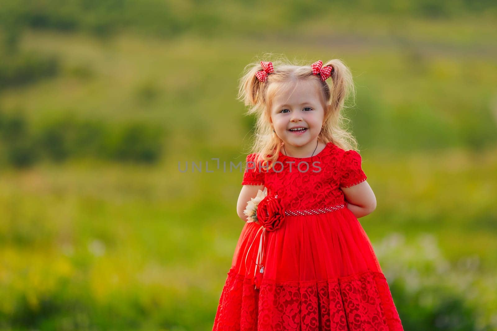 little girl in a red dress walks on the lawn