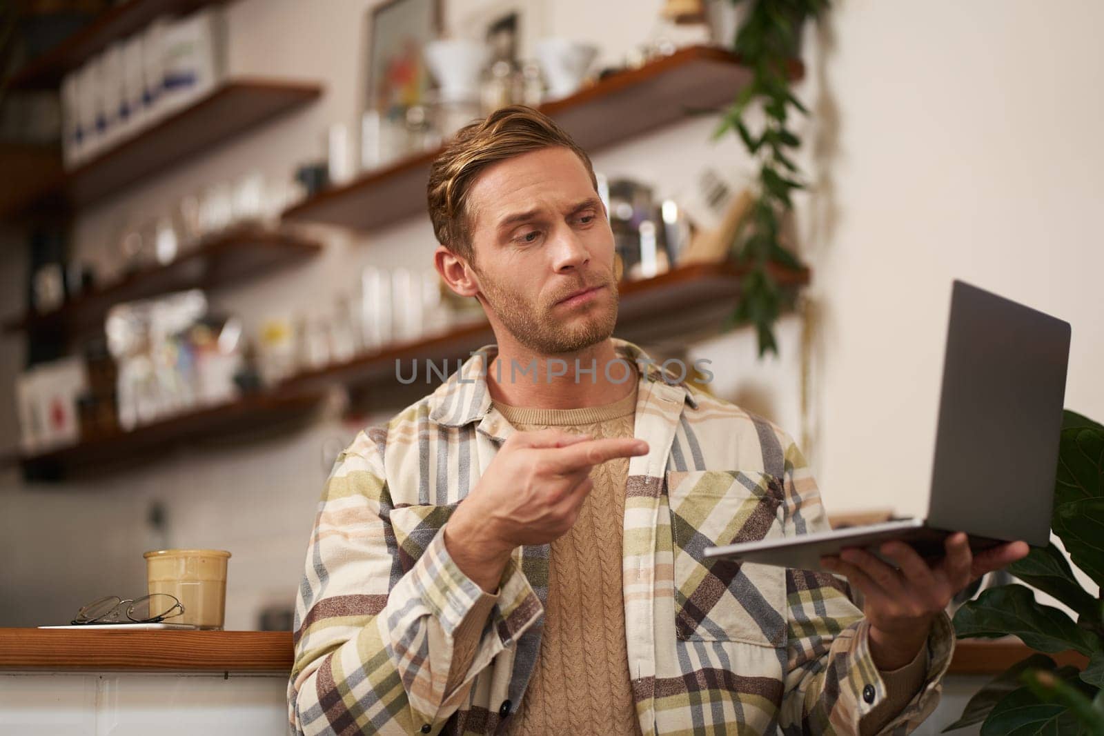 You got a point. Portrait of serious man agree with colleague, pointing finger at laptop screen, connects to video chat, has conversation with someone.