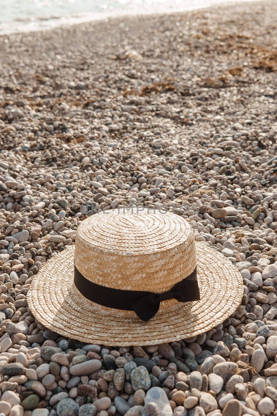 A straw hat on the beach. Pebbles on the seashore, close-up. The natural background. by Annu1tochka