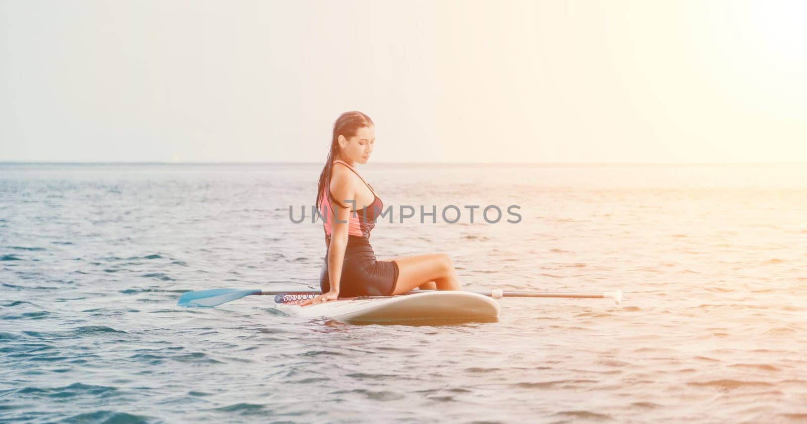 Sea woman sup. Silhouette of happy young woman in pink bikini, surfing on SUP board, confident paddling through water surface. Idyllic sunset. Active lifestyle at sea or river. Slow motion