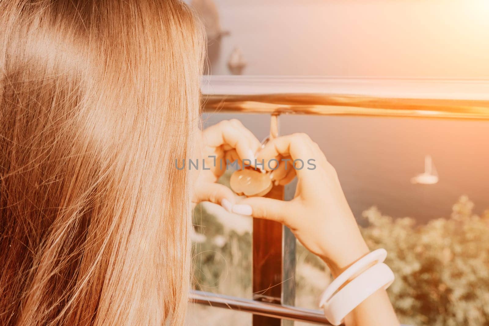 Hand, lock, heart, love, valentines day. Close up view of a woman holding a heart shaped lock that is locked onto a chain link fence.