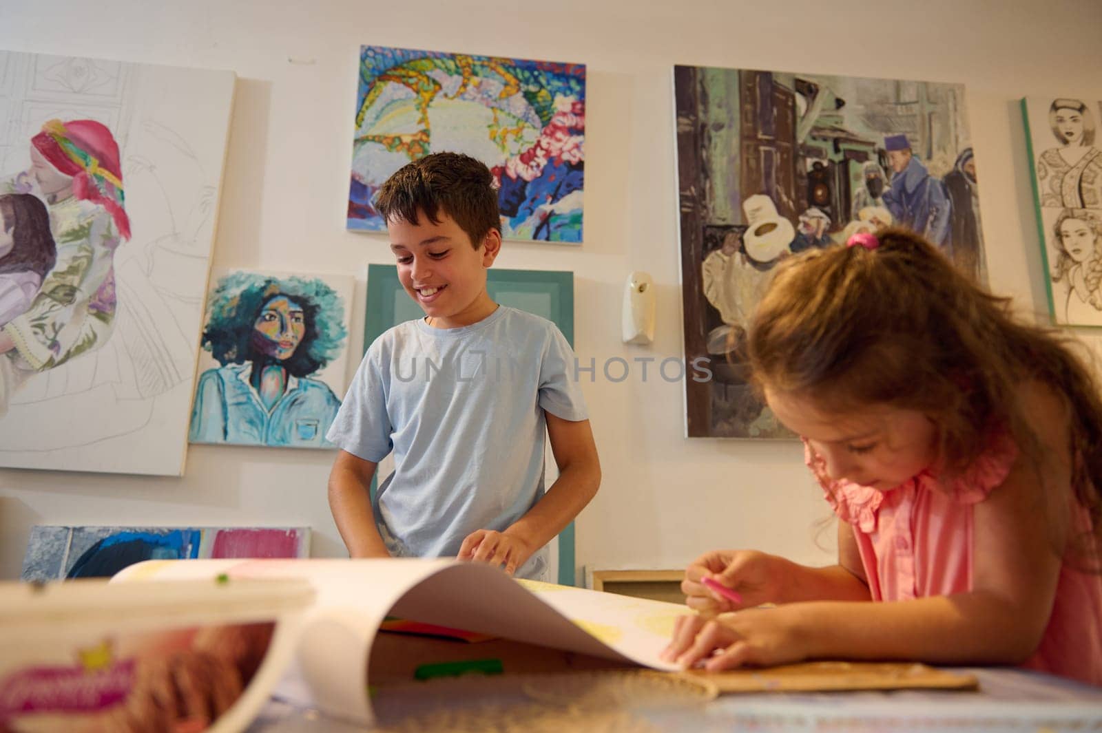 Adorable elementary age kids focused on learning fine art in creative art workshop, drawing, painting pictures