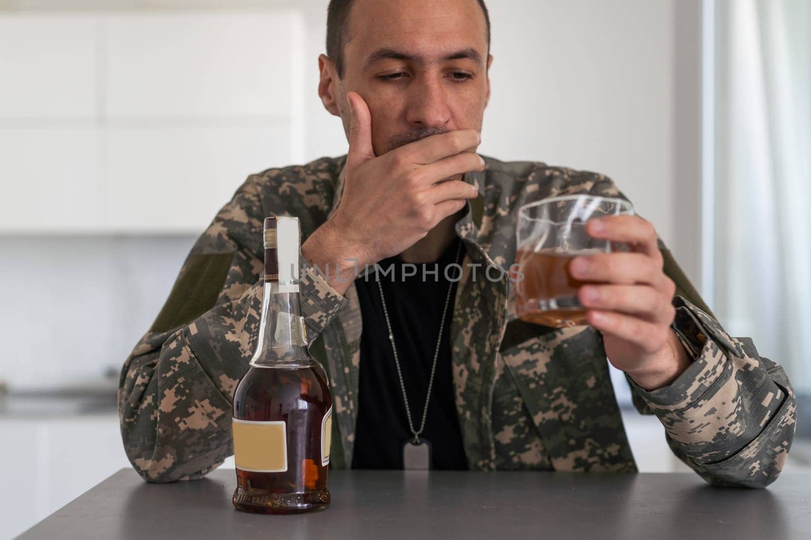 veteran holding bottle of whiskey near face while sitting in wheelchair with closed eyes. High quality photo