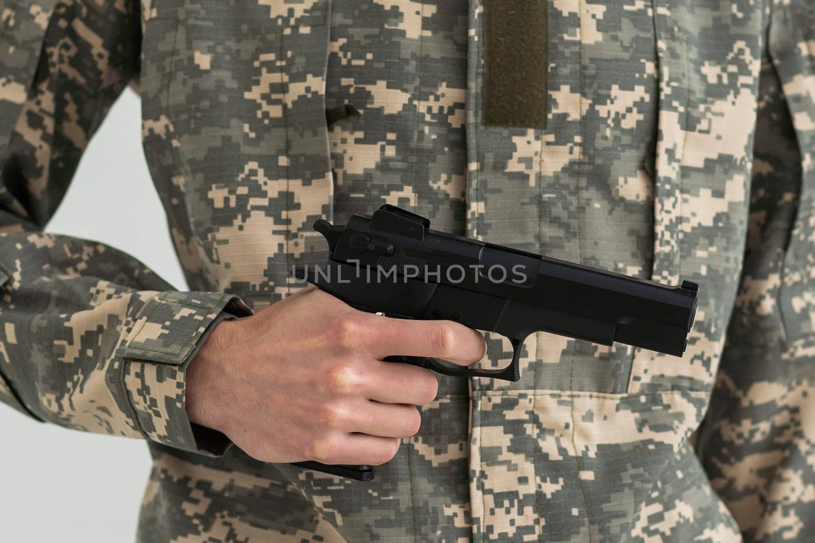 Military man holding a gun in hand.