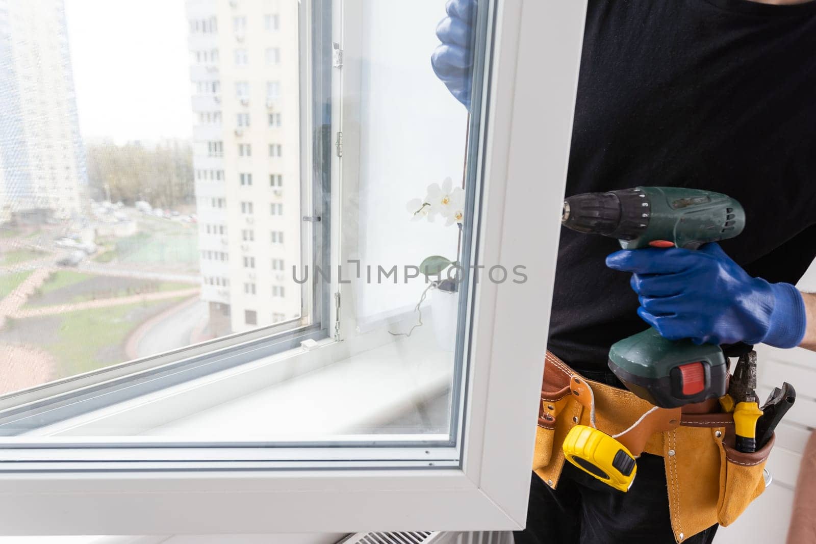 Man in a blue shirt does window installation. High quality photo