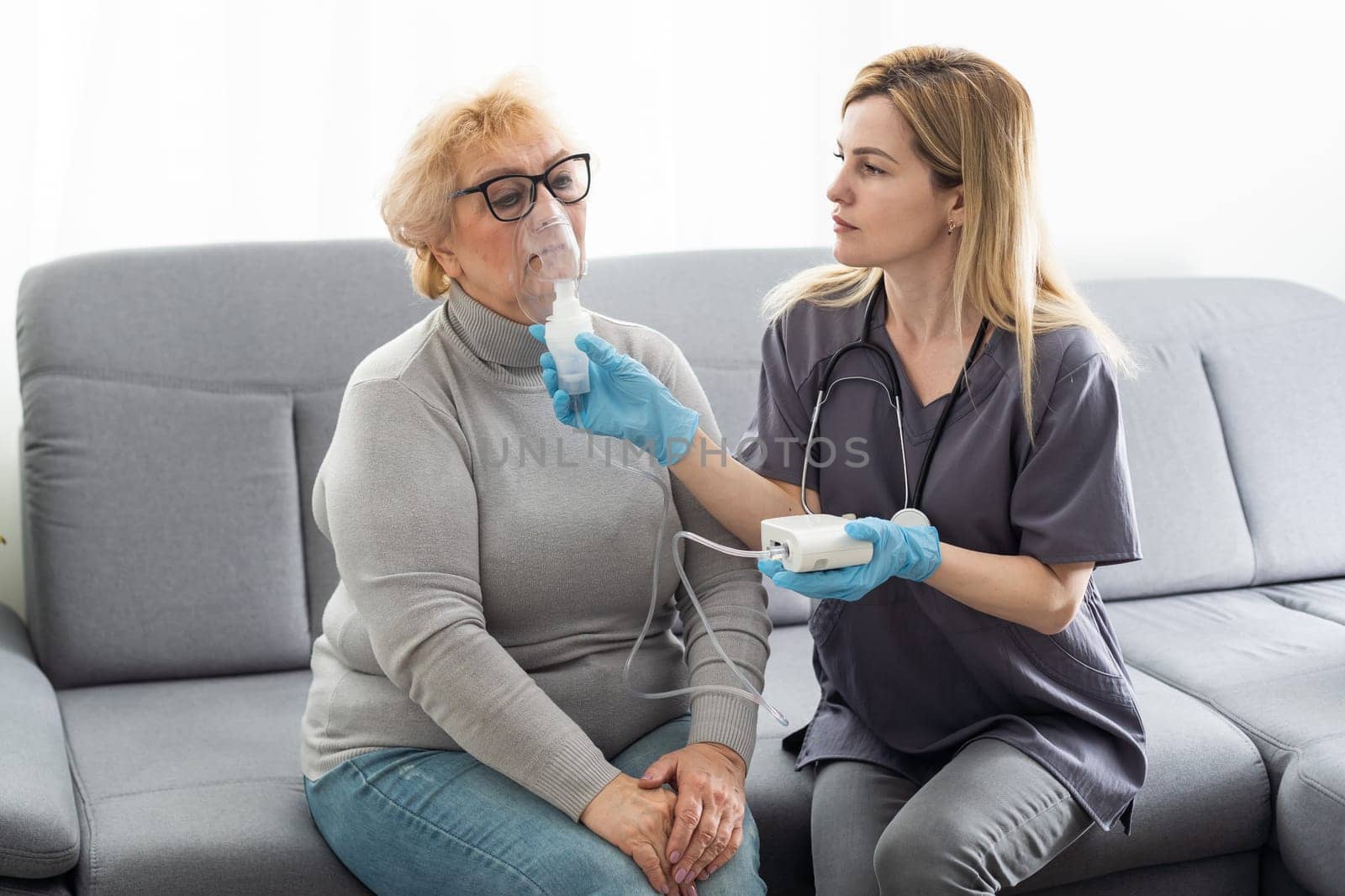 Elderly woman using inhaler for asthma and respiratory diseases at home.