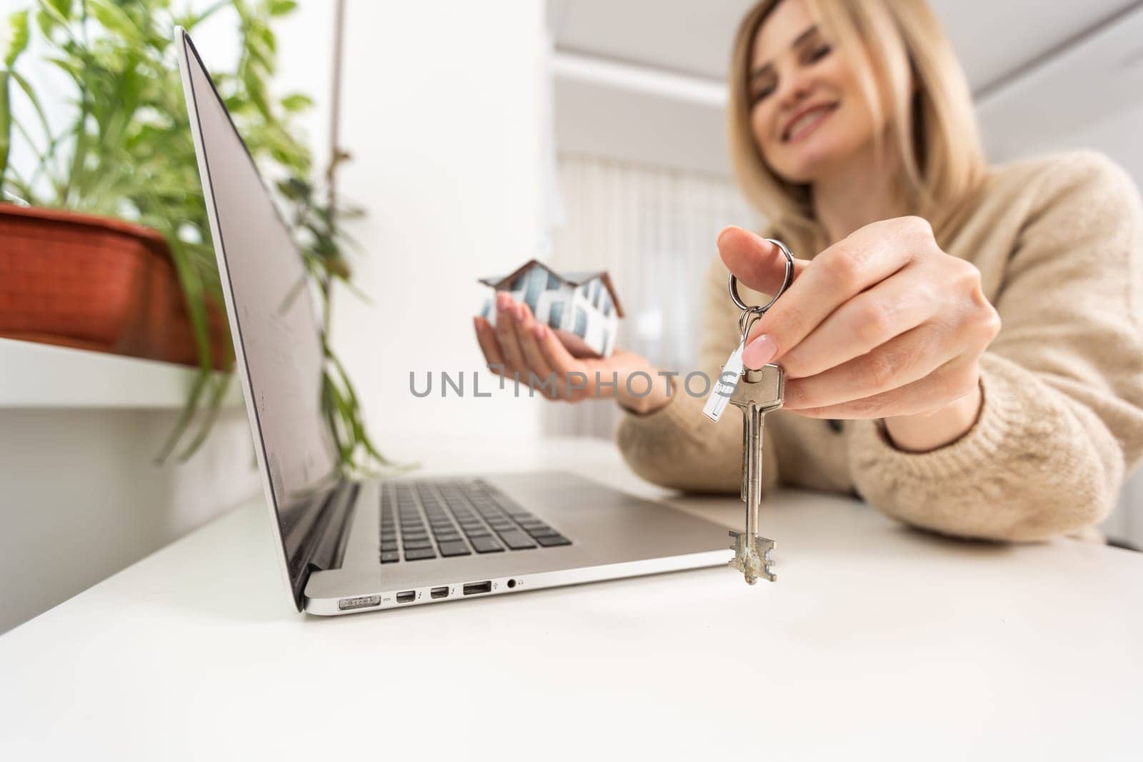 woman holding a toy house with a laptop and taxes.