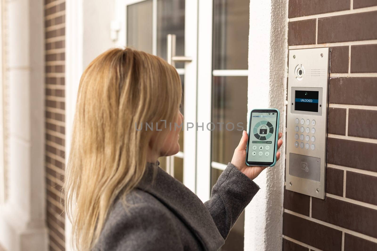 Woman touching smartphone to intercom at office