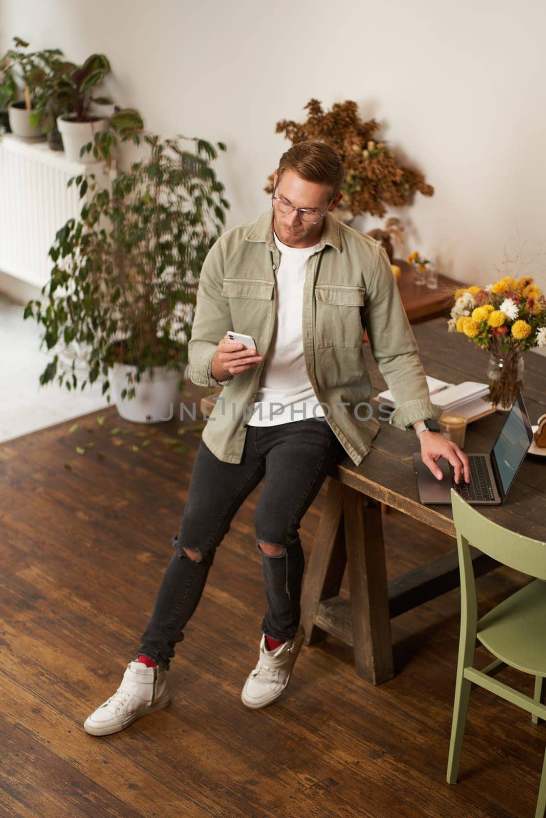 Portrait of a man in office, businessman making a phone call, having a conversation over the phone, receive a call, standing in office, leaning on table by Benzoix