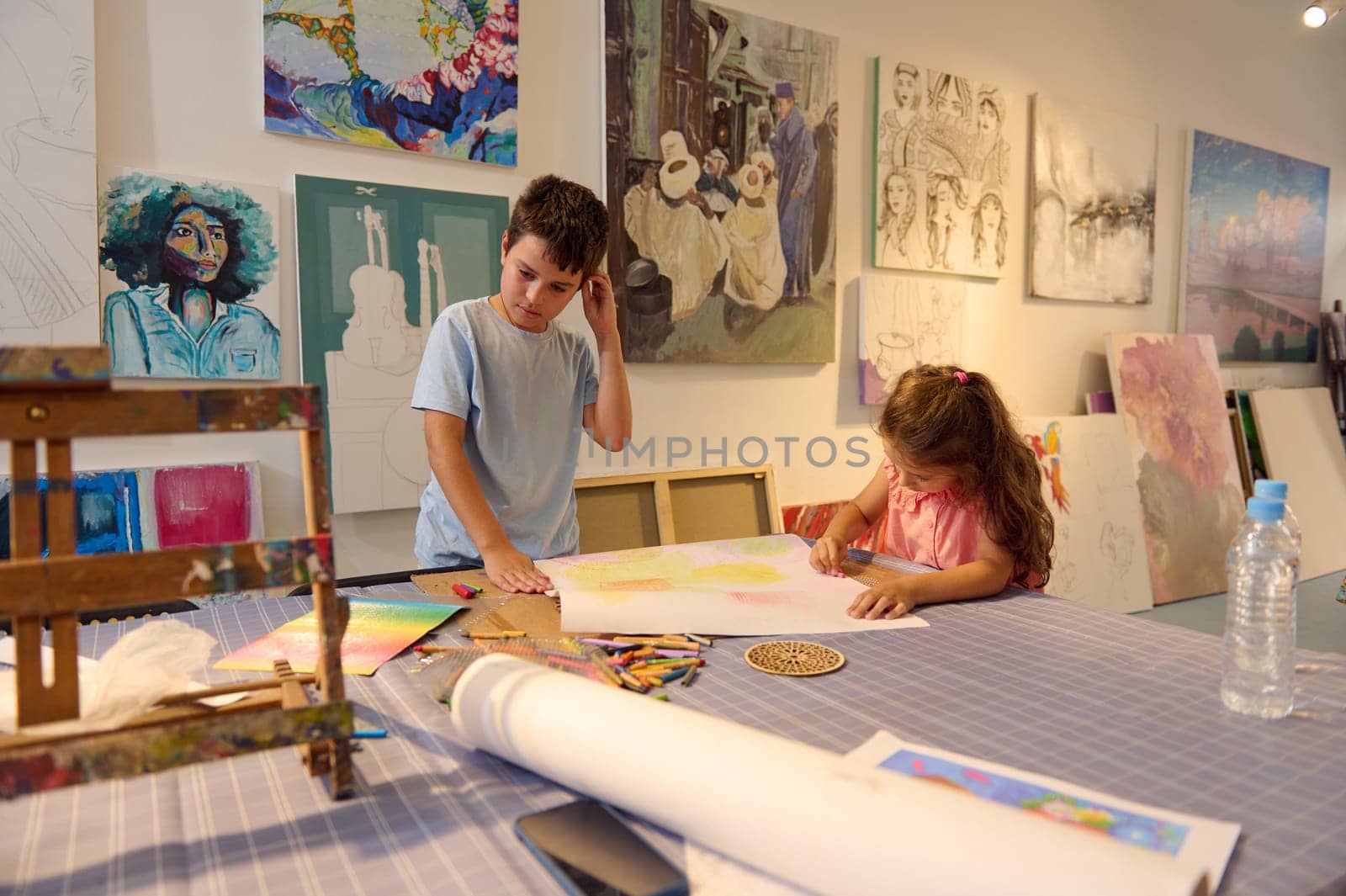Two kids leaning art in creative school. Confident portrait of a Caucasian elementary age children enjoying their creative hobby during visual art class in primary school or art workshop