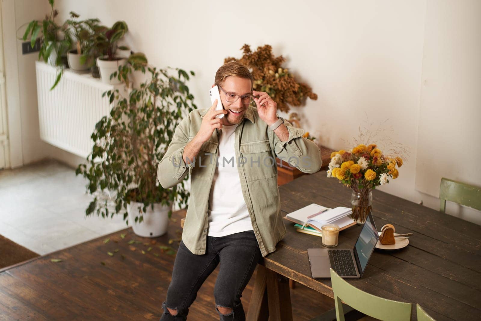 Portrait of a man in office, businessman making a phone call, having a conversation over the phone, receive a call, standing in office, leaning on table by Benzoix