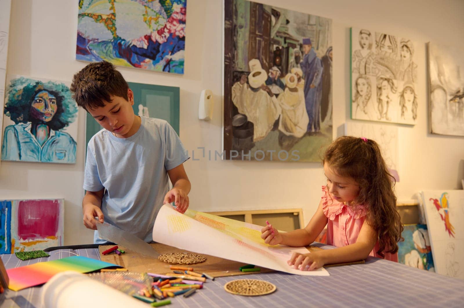 Adorable little girl and teenage boy drawing picture in the art class