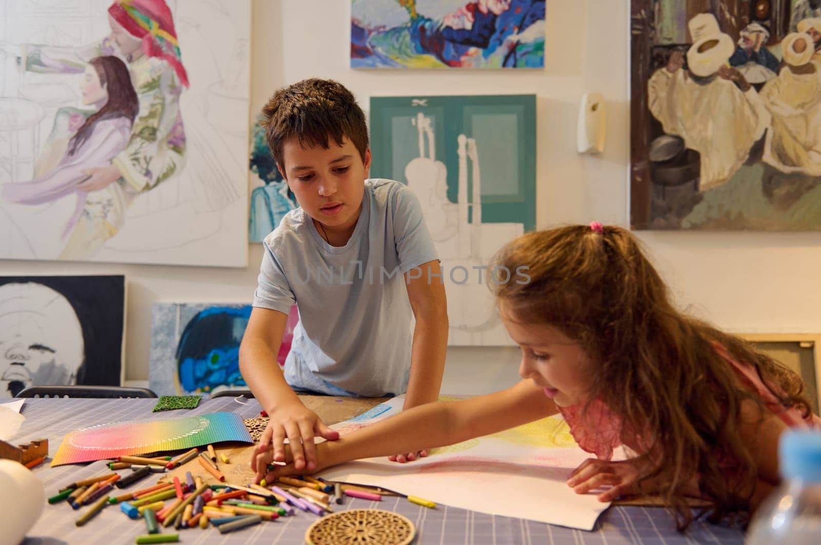 Adorable children and friends paint colorful space pictures indoors in kindergarten. Kids being creative painting science fiction drawings with colors on a big sheet. art education for kids