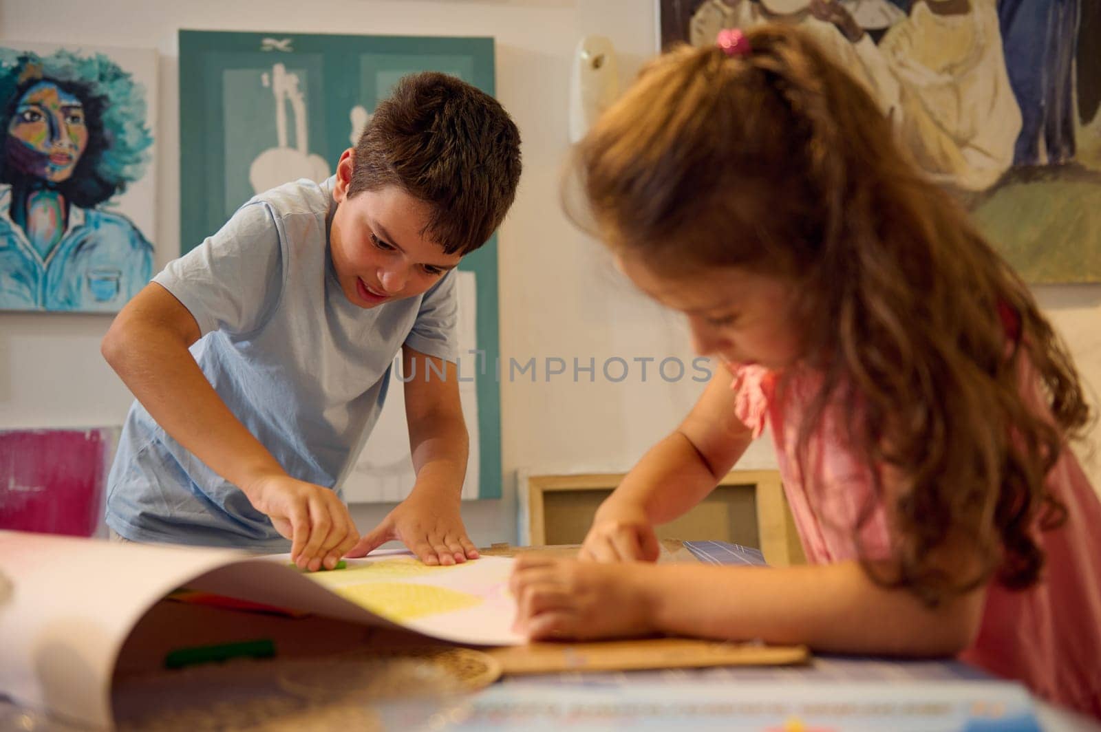 Two children, elementary age schoolkids drawing picture during art class. Teenage boy and little girl learning art in the creative art school. Fine art. Artistic education.