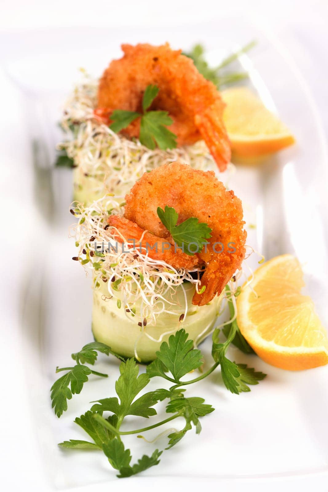 Cucumber appetizer with fried breaded shrimp on a bed of microgreens