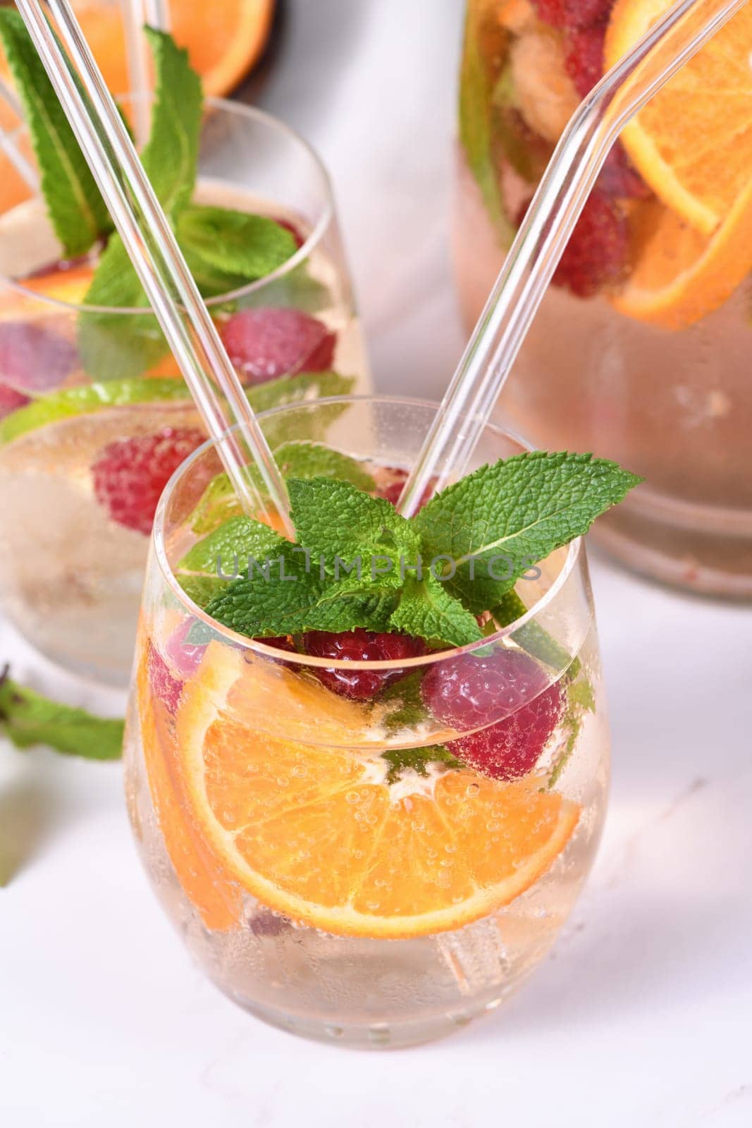 Summer Sangria cocktail or lemonade with raspberry, orange and mint. Refreshing organic non-alcoholic, Detox vitaminized healthy drink, fruit in a in a glass. Quench your thirst on a hot day.