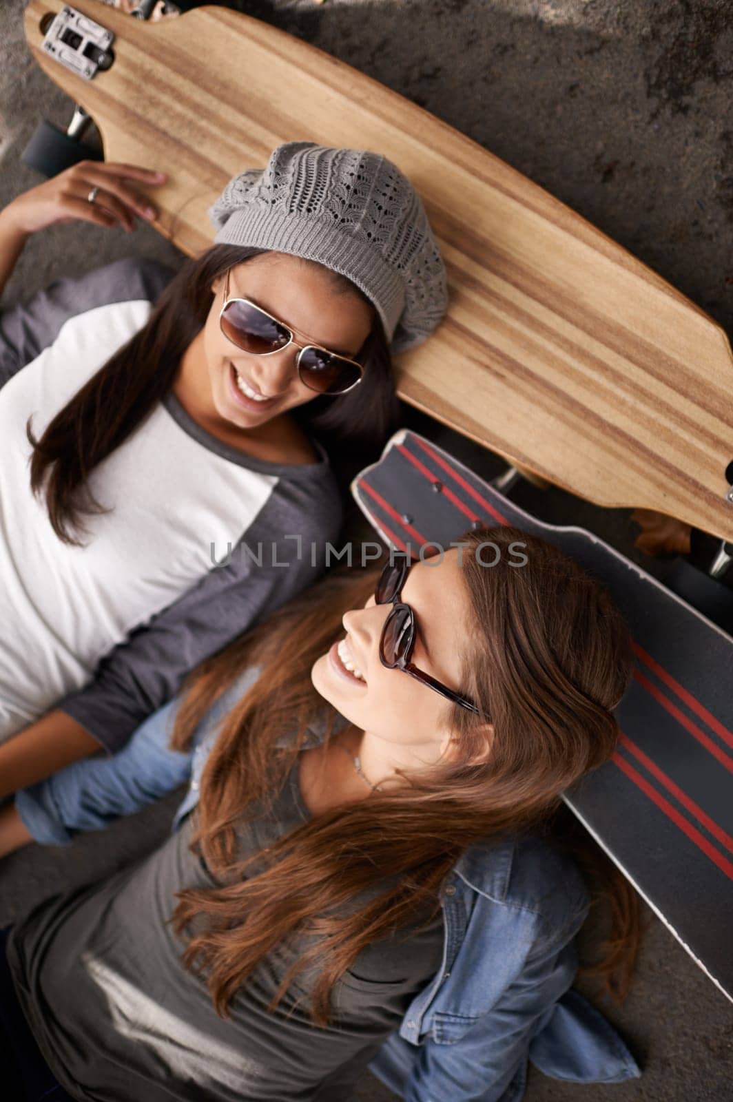 Happy, friends and above of women with skateboard for exercise, training and competition in city. Skate park, fashion and young people in trendy, casual and street style for sports, hobby and fitness.
