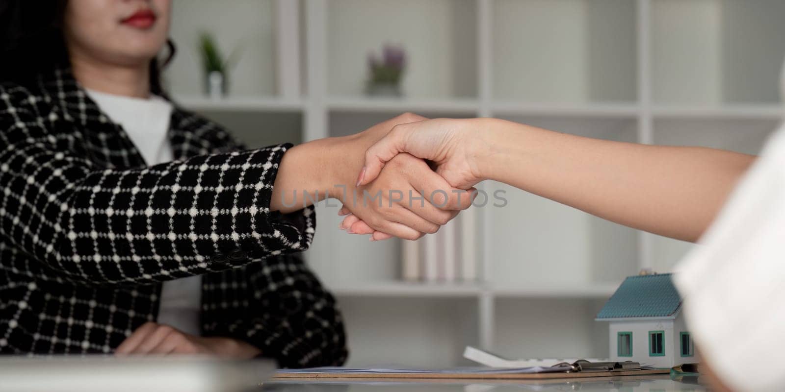 Real estate agents and customers shake hands to congratulate on signing a contract to buy a house with land and insurance, handshake and good response concept.