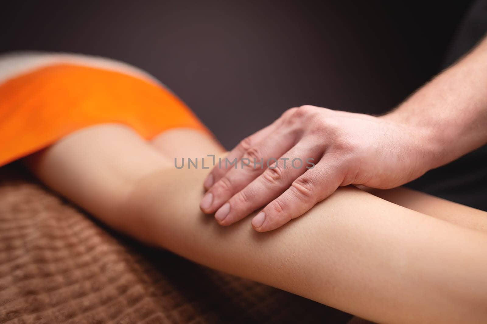 Male hands massaging the human calf muscle. Therapist applying pressure on a woman's leg.