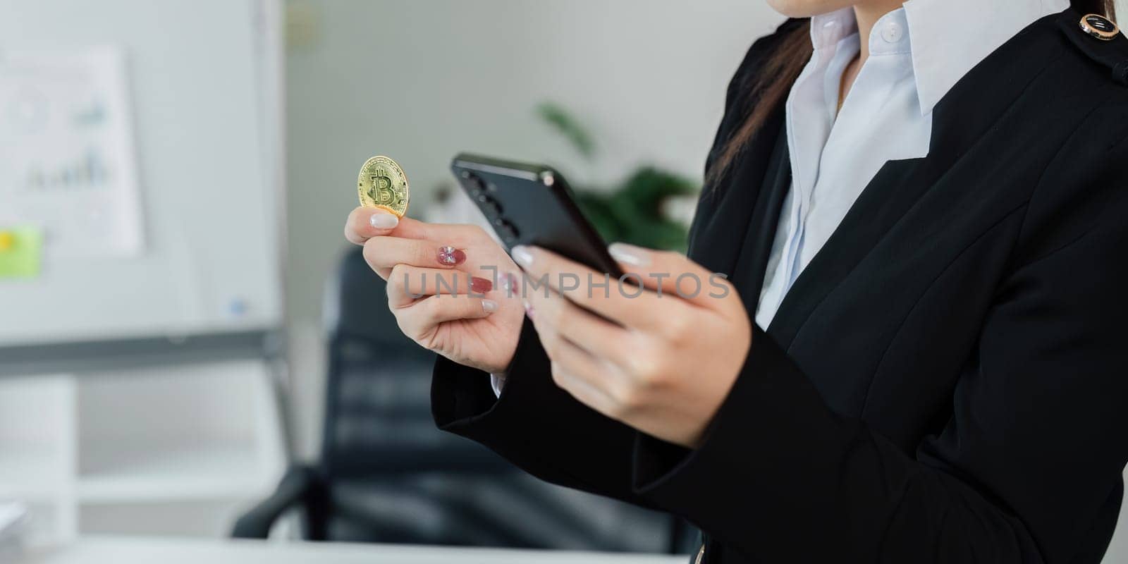A woman is holding a coin and looking at her phone. Concept of focus and determination as she looks at her phone, possibly checking stock prices or financial information. The woman's attire