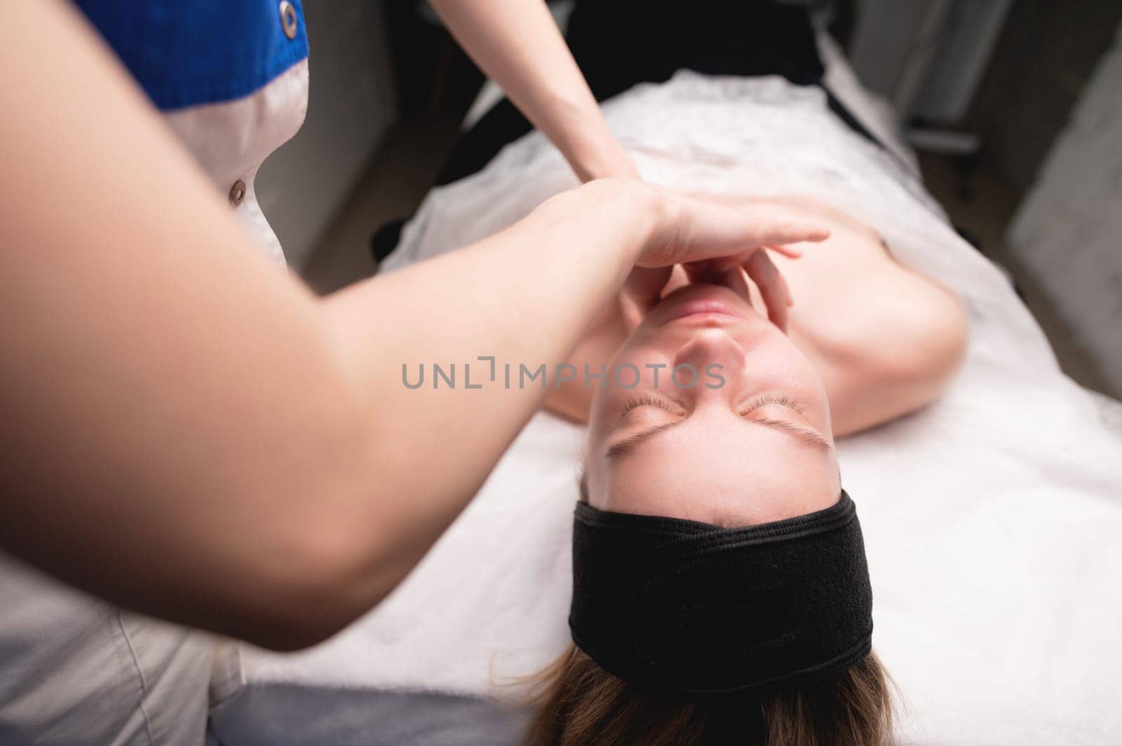 Cosmetic facial massage procedure. Close-up of the face of a young woman lying on her back, doing a face lifting massage, pinching and rolling technique by yanik88