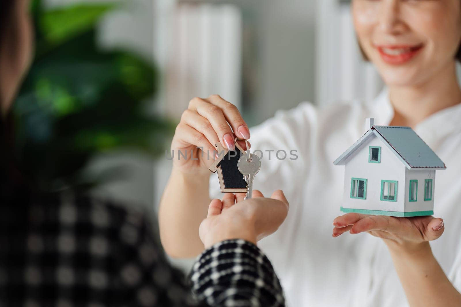 Real estate agent holding key and house and give it to client after signing agreement by itchaznong