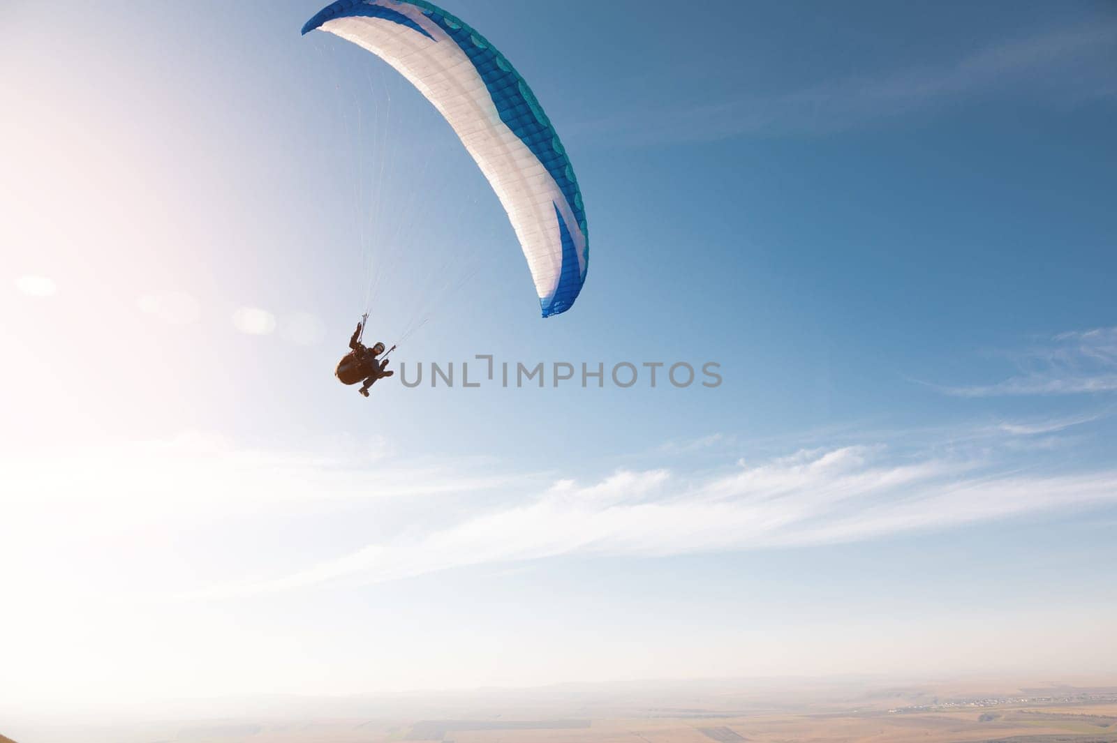 A paraglider with a blue parachute fly. A male flyght on the sky and lifts a paraglider into the air by yanik88
