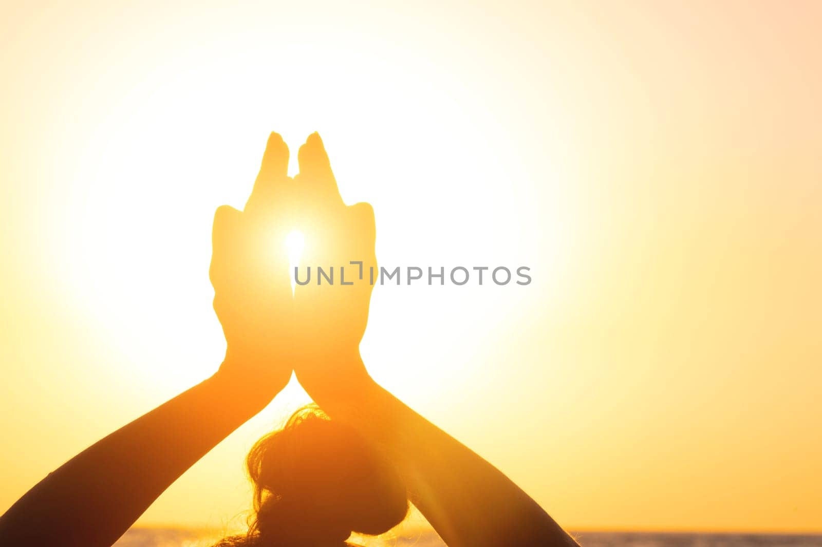 Close-up Yoga woman meditating at serene sunset or sunrise on the beach. The girl relaxes in the lotus position. Fingers folded in mudras