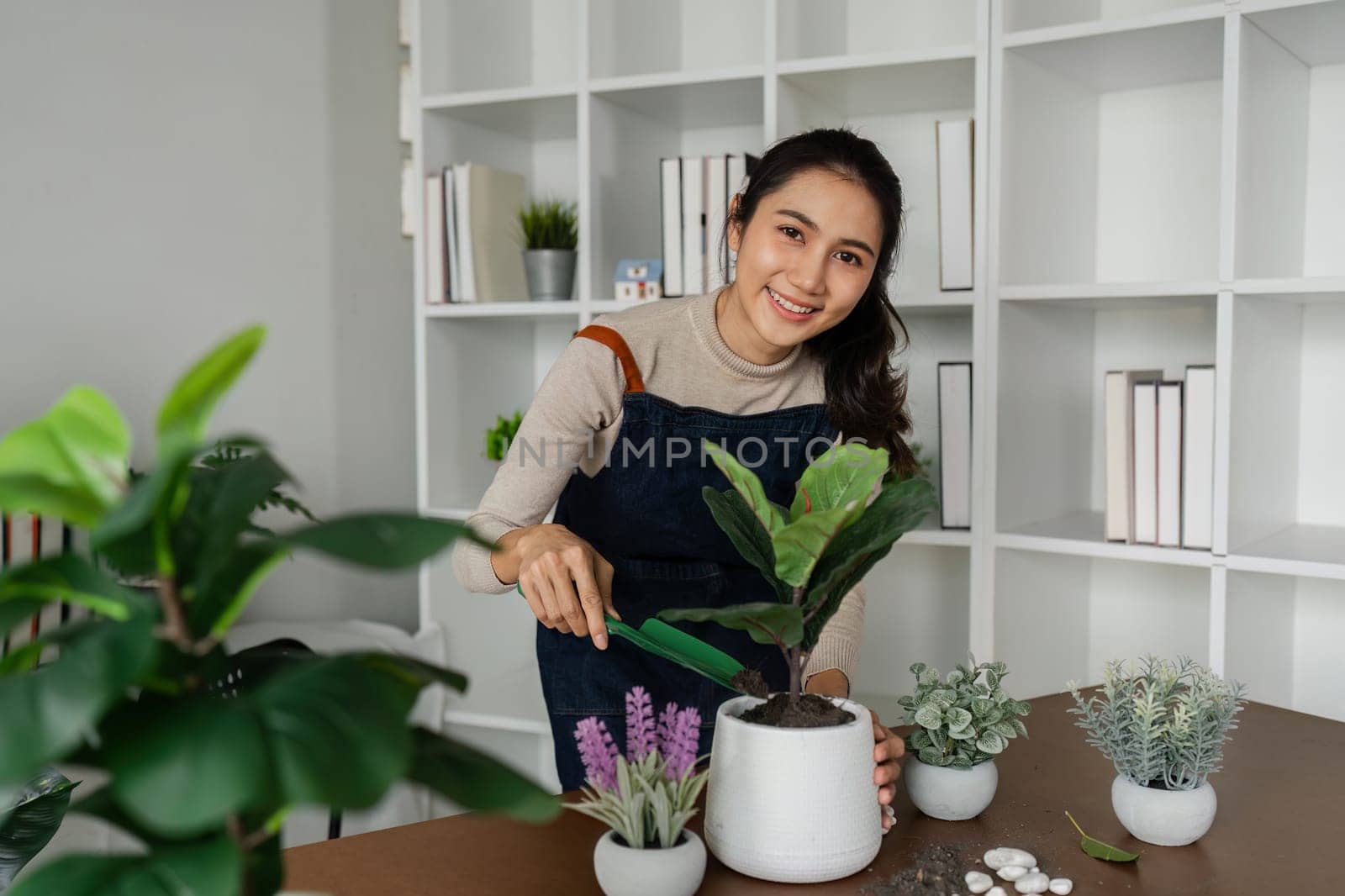 Woman looking at camera while putting plants in pots, doing hobby.