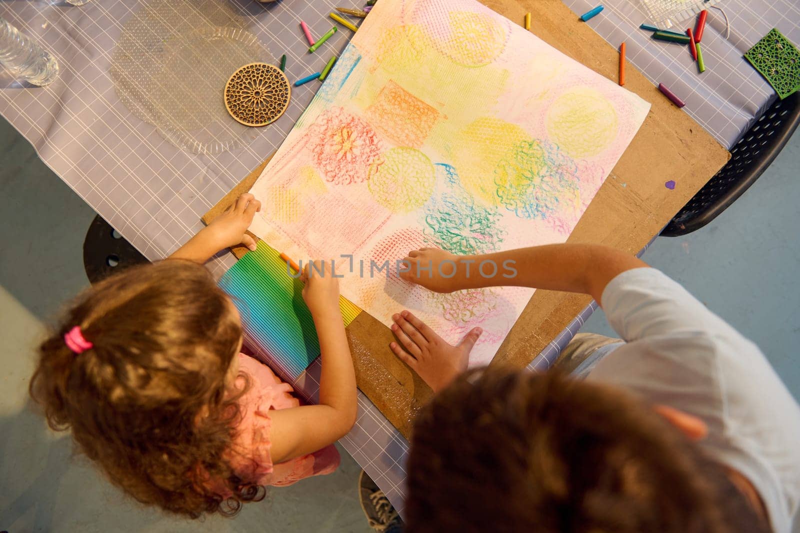 Overhead view of children, elementary age schoolkids drawing picture during art class. Teenage boy and little girl learning art in the creative art school. Fine art. Artistic education.