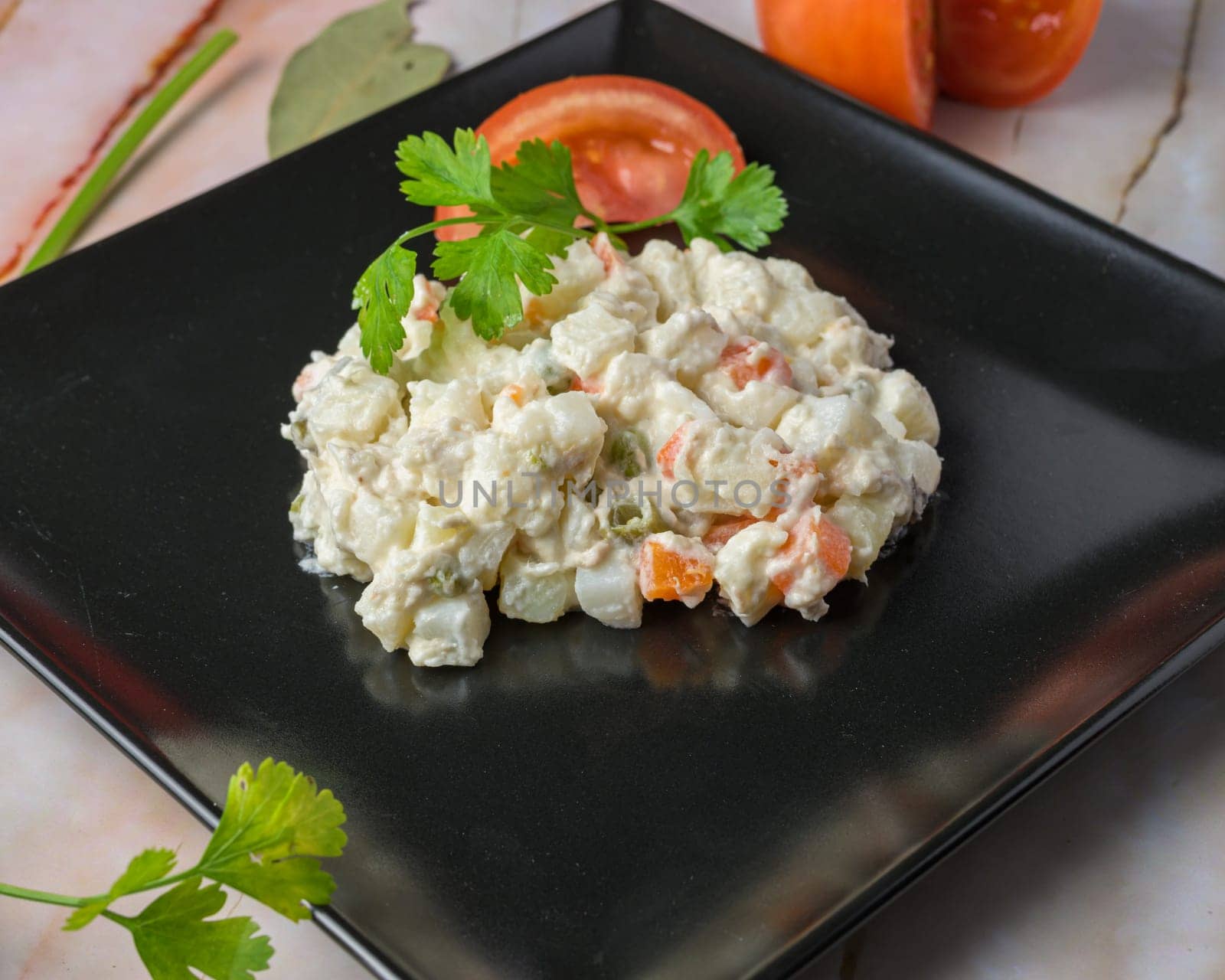 Russian salad Creamy potato salad garnished with parsley on a black plate, typical food, typical mediterranean mallorcan cuisine typical from balearic islands mallorca, spain,