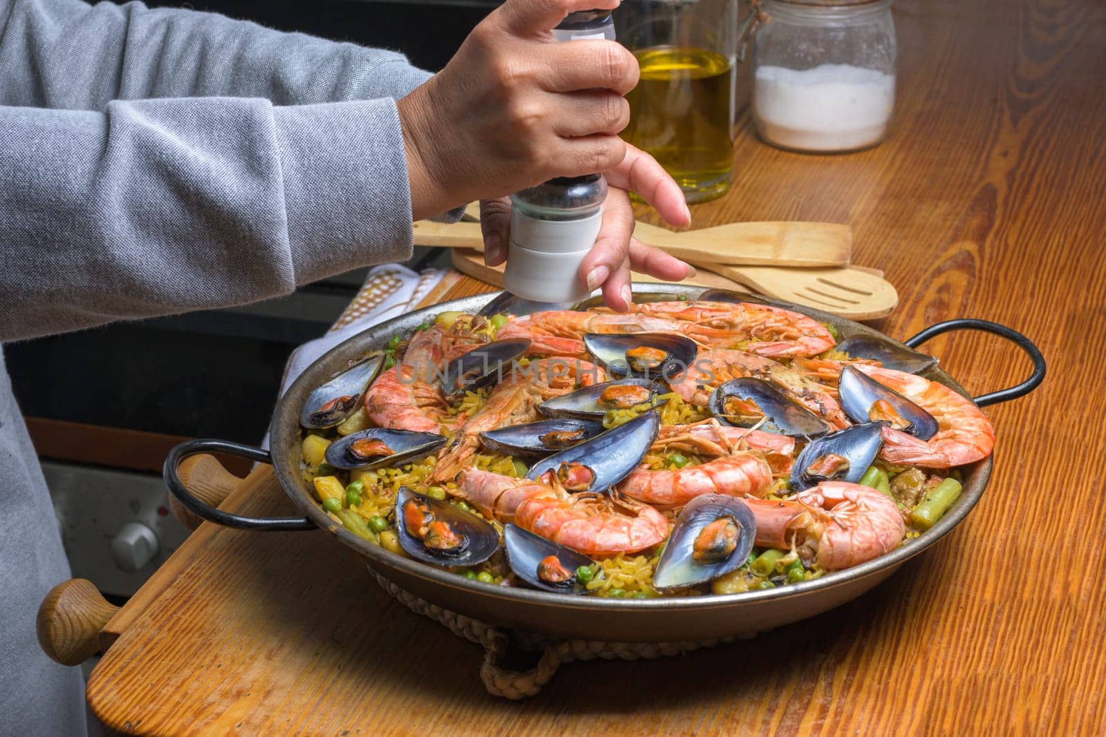 Person seasoning a paella with prawns and mussels, evoking home cooking, typical Spanish cuisine, Majorca, Balearic Islands, Spain