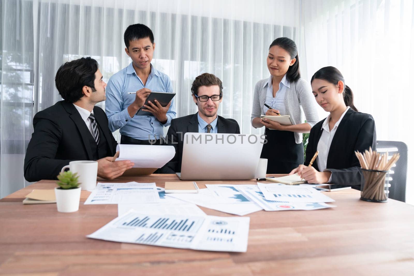 Diverse group of business analyst team analyzing financial data report paper on office table. Chart and graph dashboard by business intelligence analysis for strategic marketing planning Habiliment