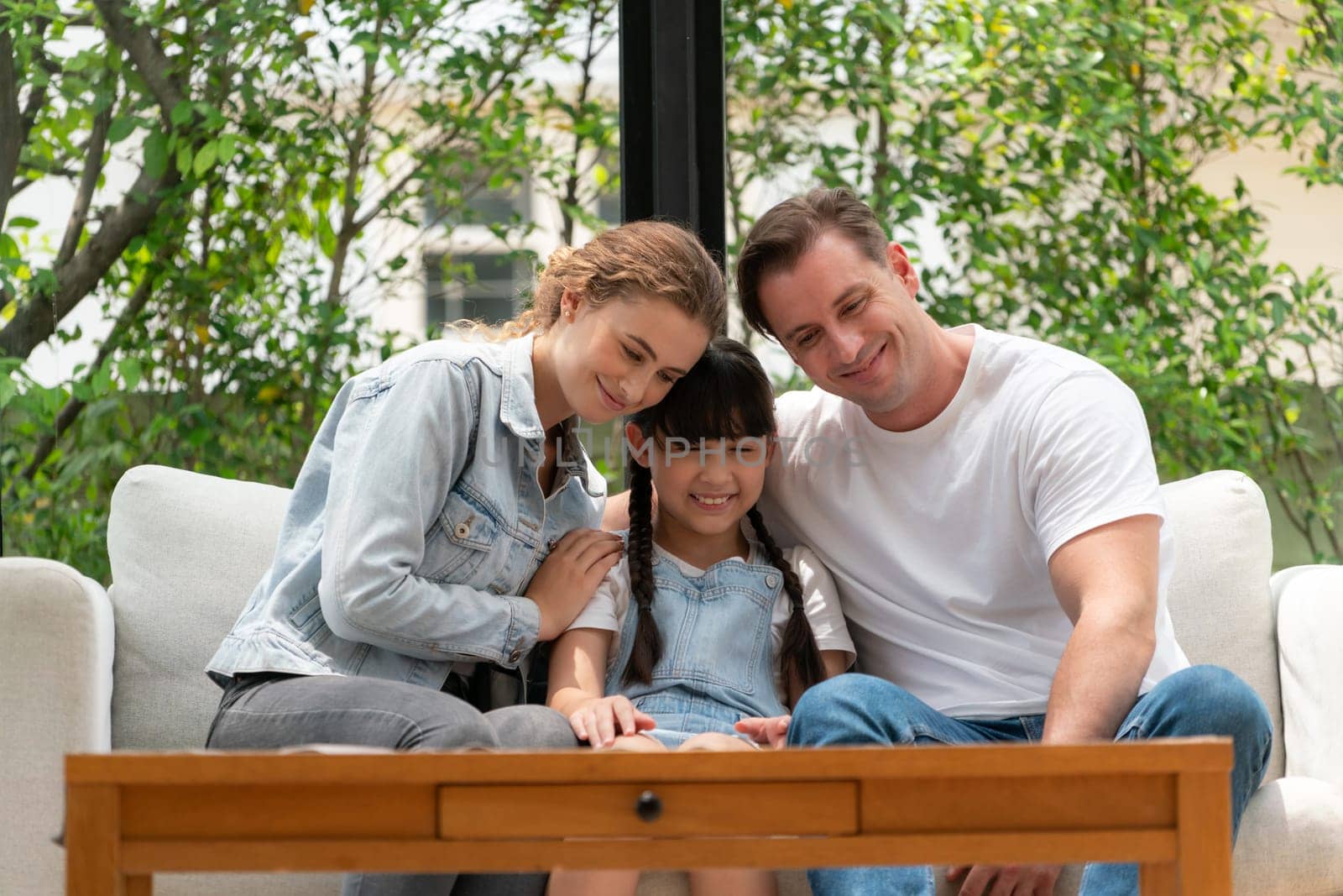 Parents comforting their daughter with loving hug, helping her feel secure and protected from fear, rest her head on shoulder. Happy family love and child care support concept. Synchronos