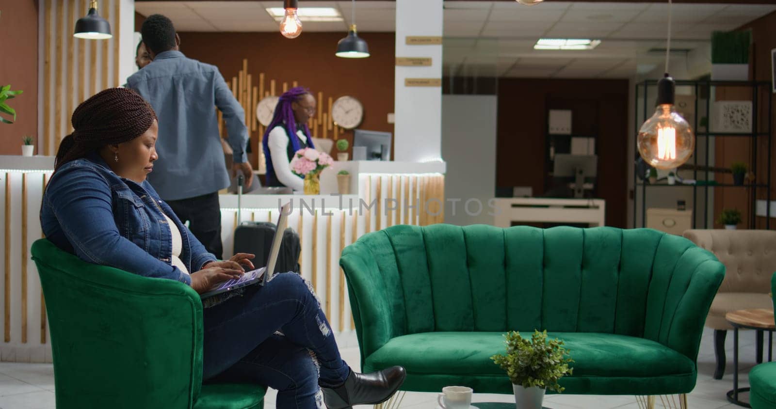 Customer checking social media webpage in lounge area, waiting for accommodation at five star hotel. Young woman travelling on vacation and using laptop before room registration.