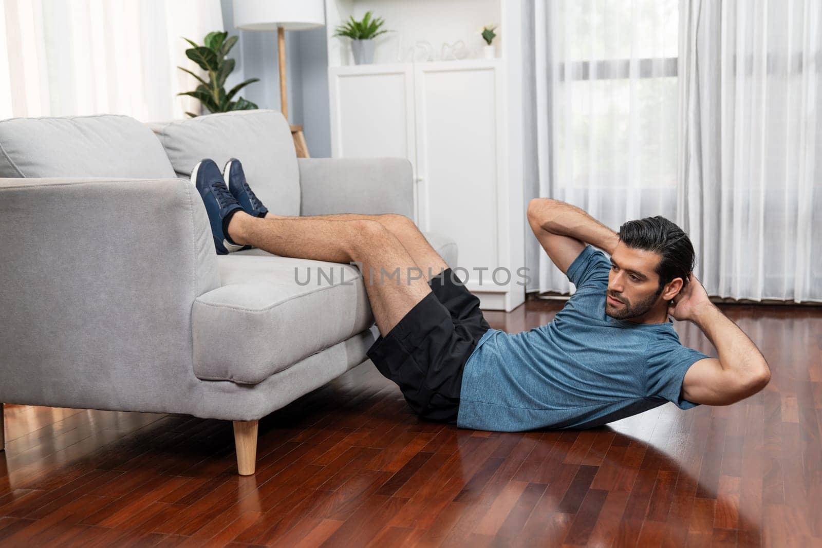 Athletic body and active sporty man using furniture for gaiety home exercise. by biancoblue